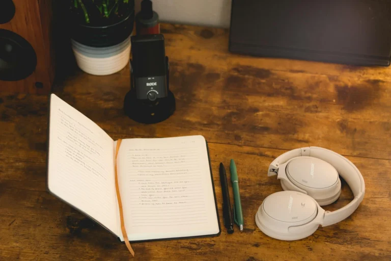 Préparation d'un teaser de podcast en prenant des notes, avec casque audio et micro posés sur une table